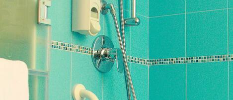 A bathroom with turquoise tiles, a showerhead, a handheld shower, a towel rack, and a toilet paper holder.
