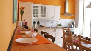A kitchen with white cabinets, a wooden table, and orange accents.