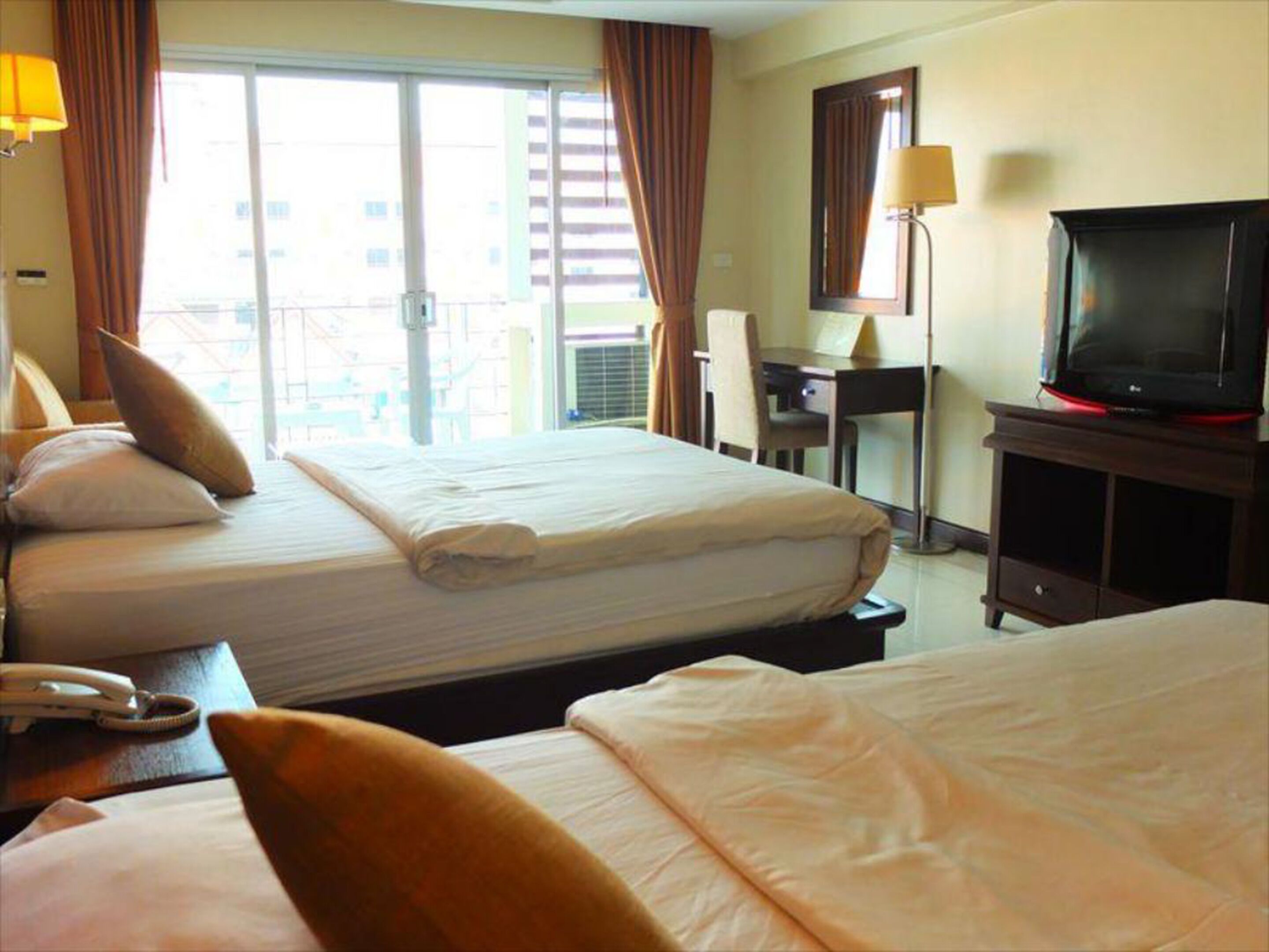 Una habitación de hotel con dos camas, un escritorio, una silla, un televisor y un teléfono.