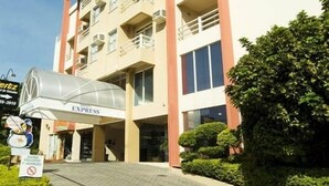 A multi-story hotel with a central entrance, balconies on each floor, and a clear sky. - Ingleses Express (Florianopolis)