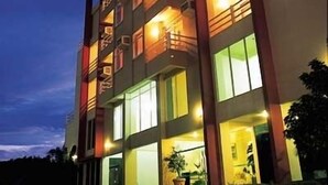 A multi-story hotel with balconies, large windows, and a well-lit entrance. - Ingleses Express (Florianopolis)