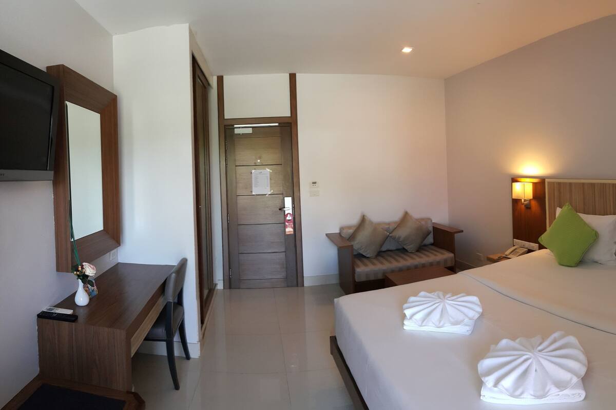 Une chambre d’hôtel comprenant un lit, une table de chevet, une lampe et un bureau avec une chaise.