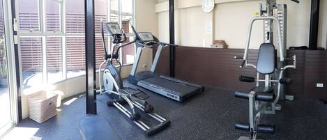 A gym with cardio machines, weightlifting equipment, and a clock on the wall.