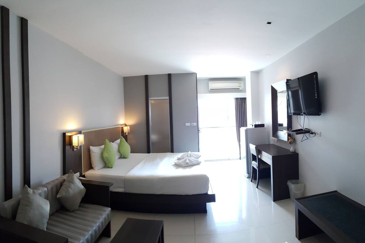 Une chambre d’hôtel moderne équipée d’un lit, d’un canapé, d’un bureau et d’une télévision.