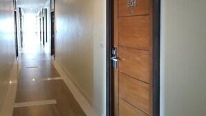 A hallway with a wooden door labeled 506, a light-colored floor, and a ceiling with recessed lighting.