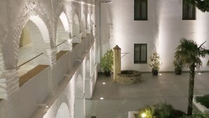 A courtyard with a white building, arched walkways, and potted plants. - Hotel Convento Aracena & Spa (Aracena)