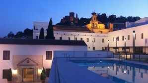 A swimming pool area with a building in the background. - Hotel Convento Aracena & Spa (Aracena)