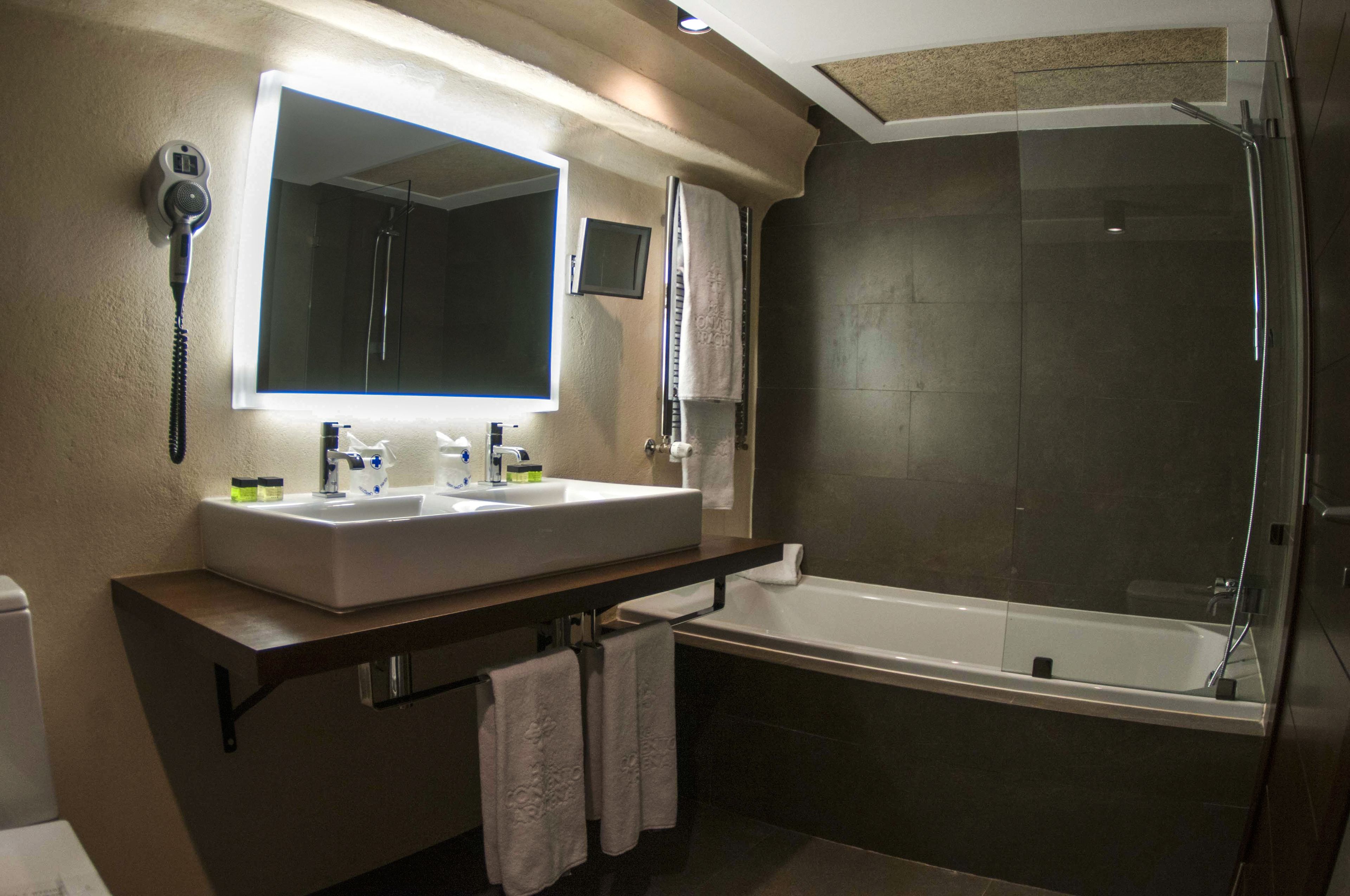 A modern bathroom with a dual sink vanity, a large mirror, a glass-enclosed shower, and a built-in toilet.