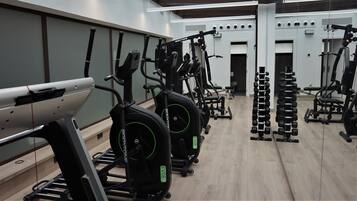A gym with cardio machines, weightlifting equipment, and mirrors on the walls.