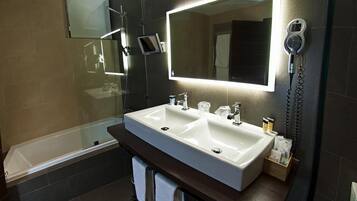 A modern bathroom with a dual sink vanity, a large mirror, and a hairdryer mounted on the wall.