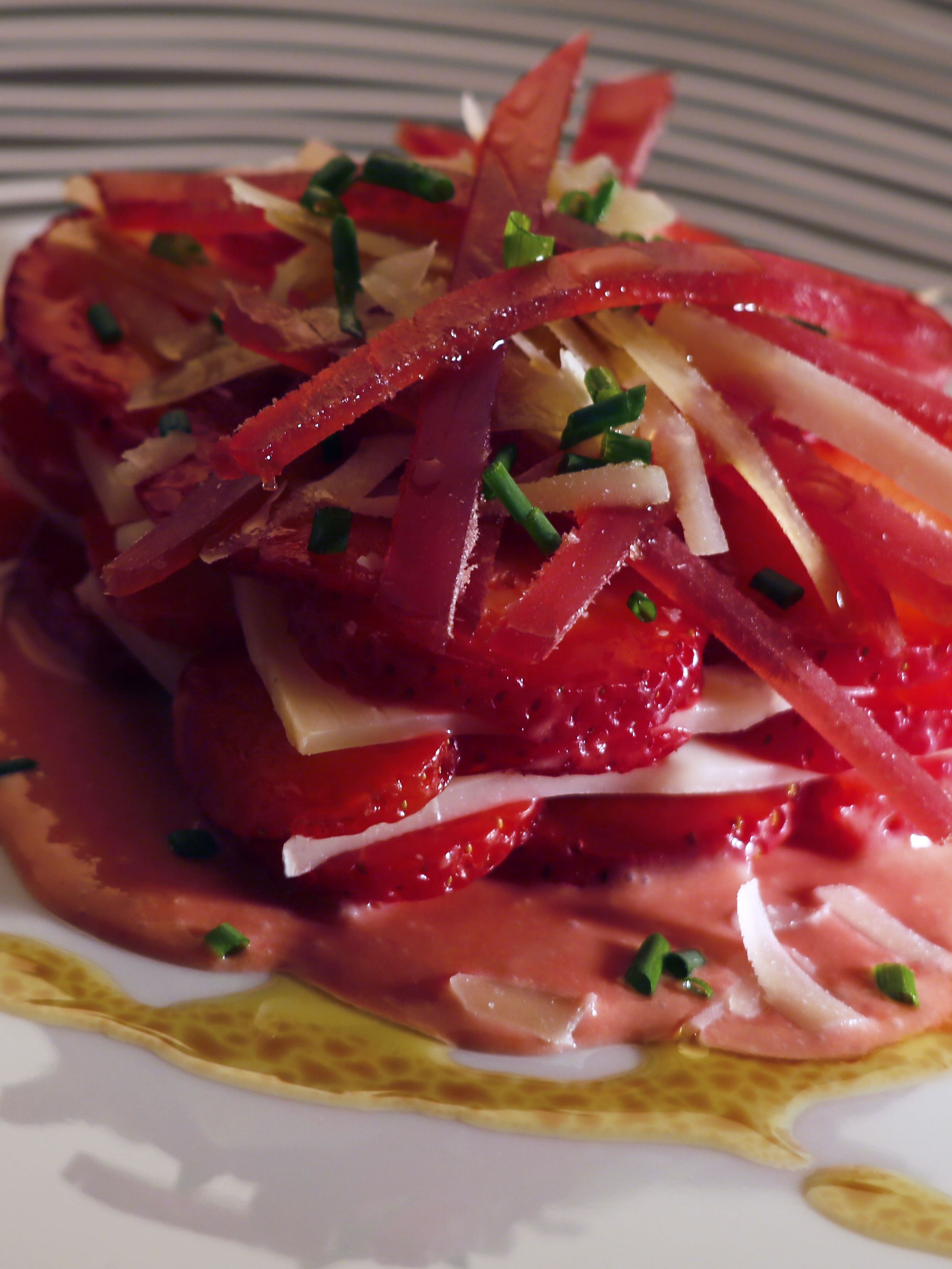 A close-up of a dish with sliced strawberries, onions, and herbs on a plate.
