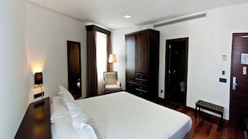 Habitación de hotel con una cama grande, una silla, un escritorio y un armario.