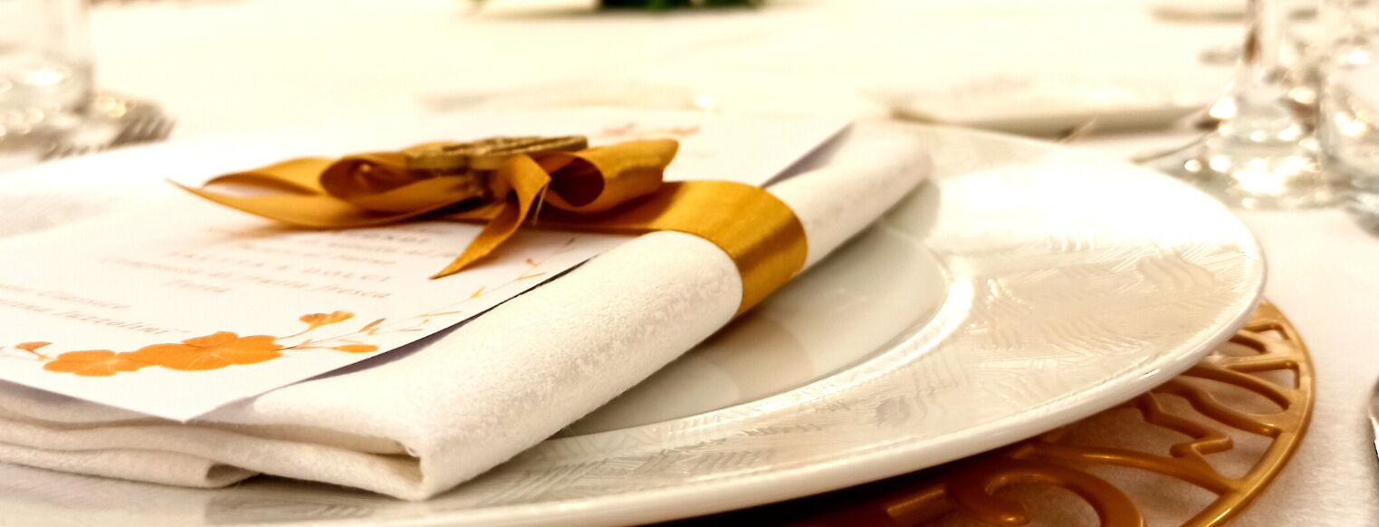 Un menú doblado con un lazo amarillo sobre un plato blanco.