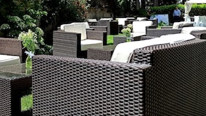 An outdoor seating area with wicker furniture and a glass table.