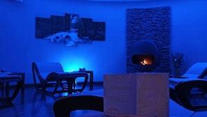 A modern lounge area with a stone fireplace, seating, and artwork on the walls.
