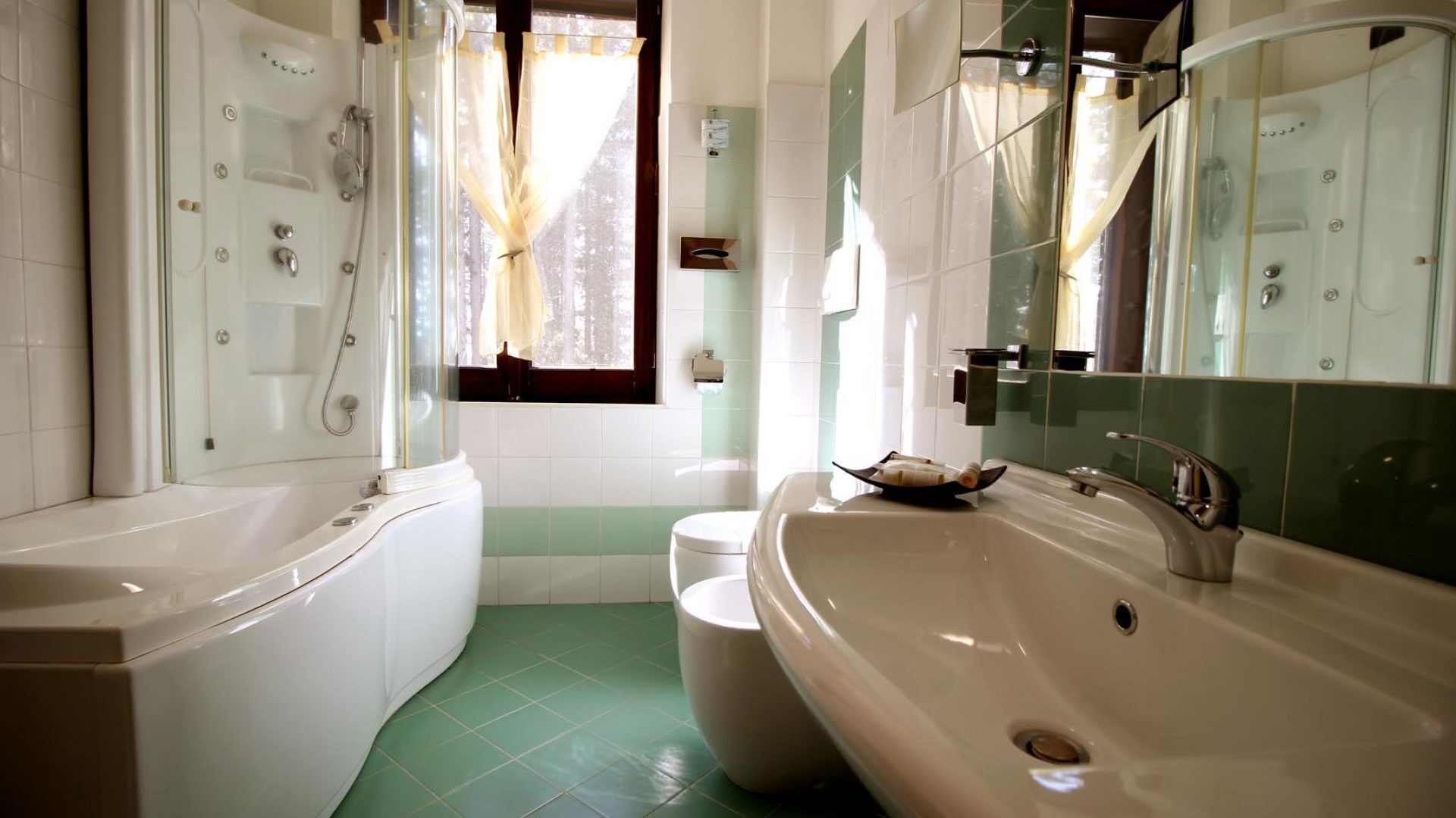 Et badeværelse med badekar, stor vask og toilet.