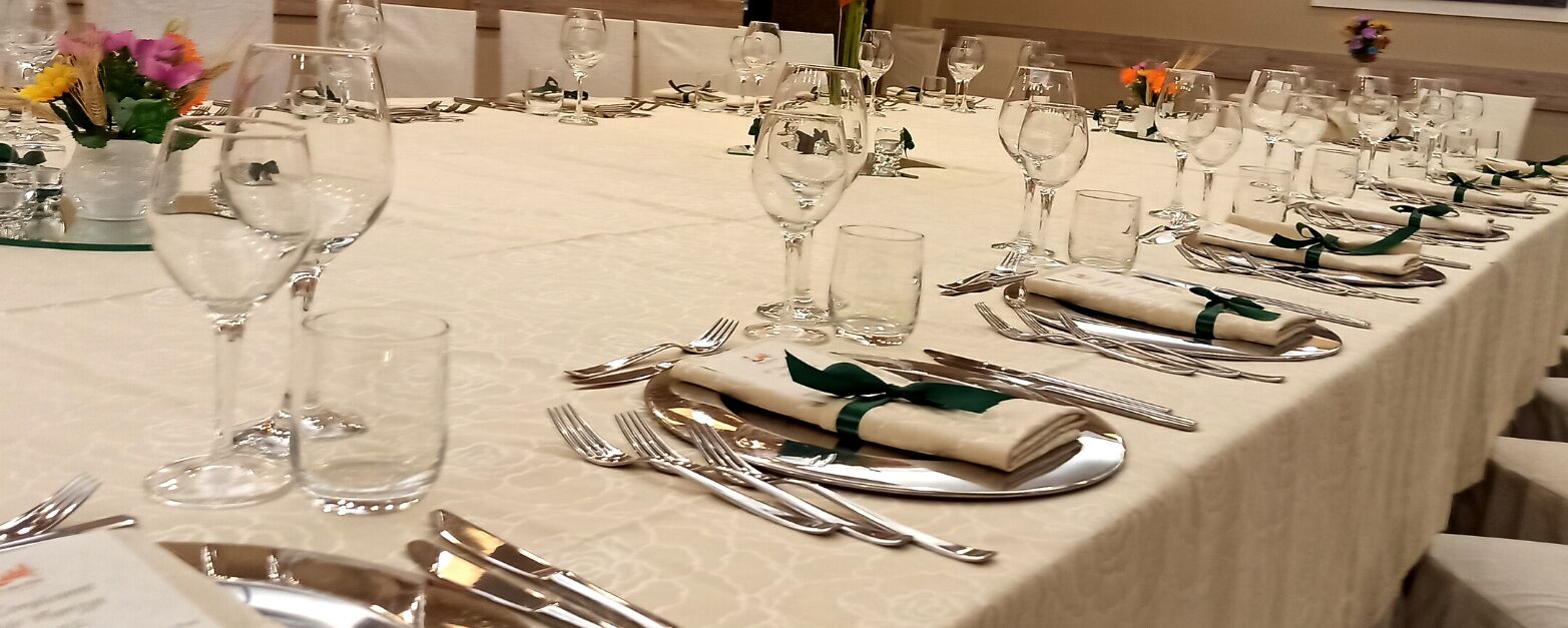 A long dining table set with multiple wine glasses, forks, knives, and napkins.