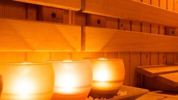 A sauna with wooden benches and three lit candles.