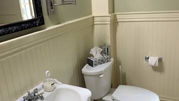 A bathroom with a white sink, a toilet, and a bidet. There is a mirror above the sink, and a toilet paper holder is visible on the wall.