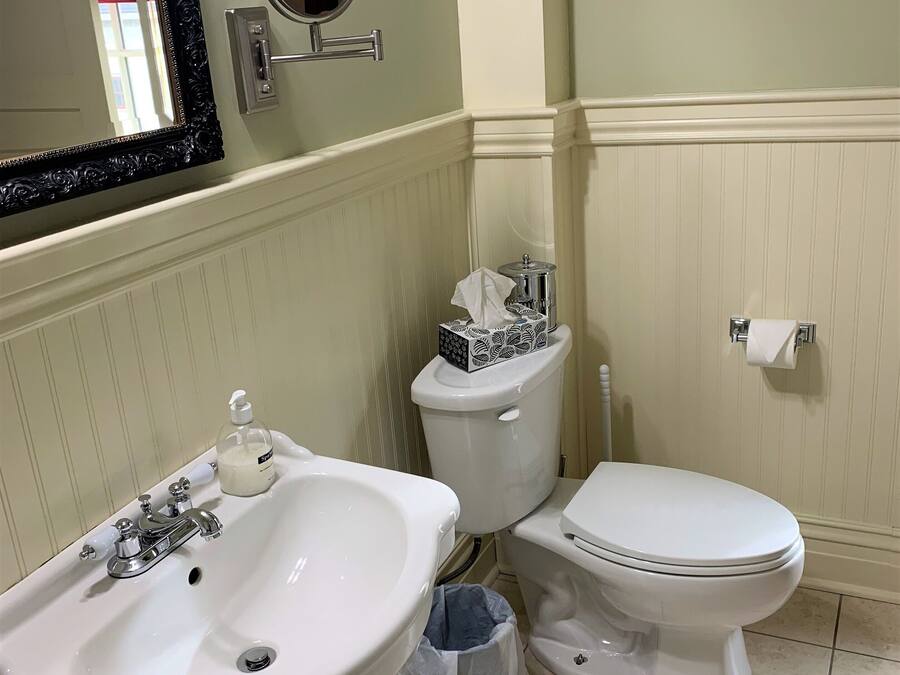 A bathroom with a white sink, a toilet, and a bidet. There is a mirror above the sink, and a toilet paper holder is visible on the wall.