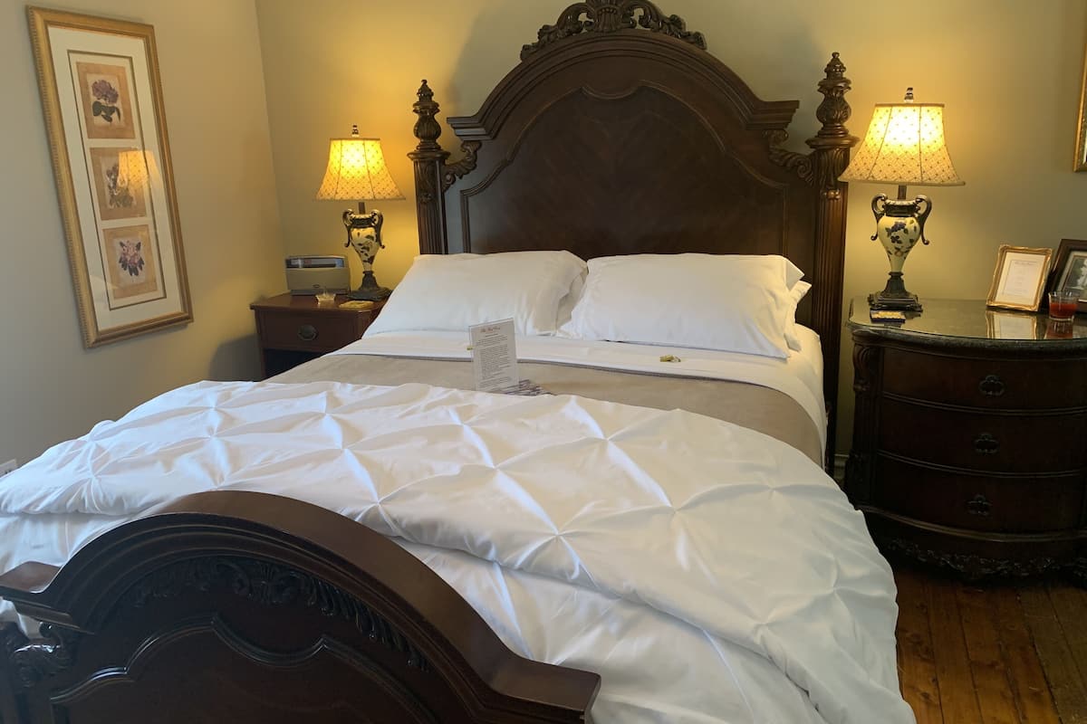 A neatly made bed with a wooden headboard, two bedside tables with lamps, and framed pictures on the wall.
