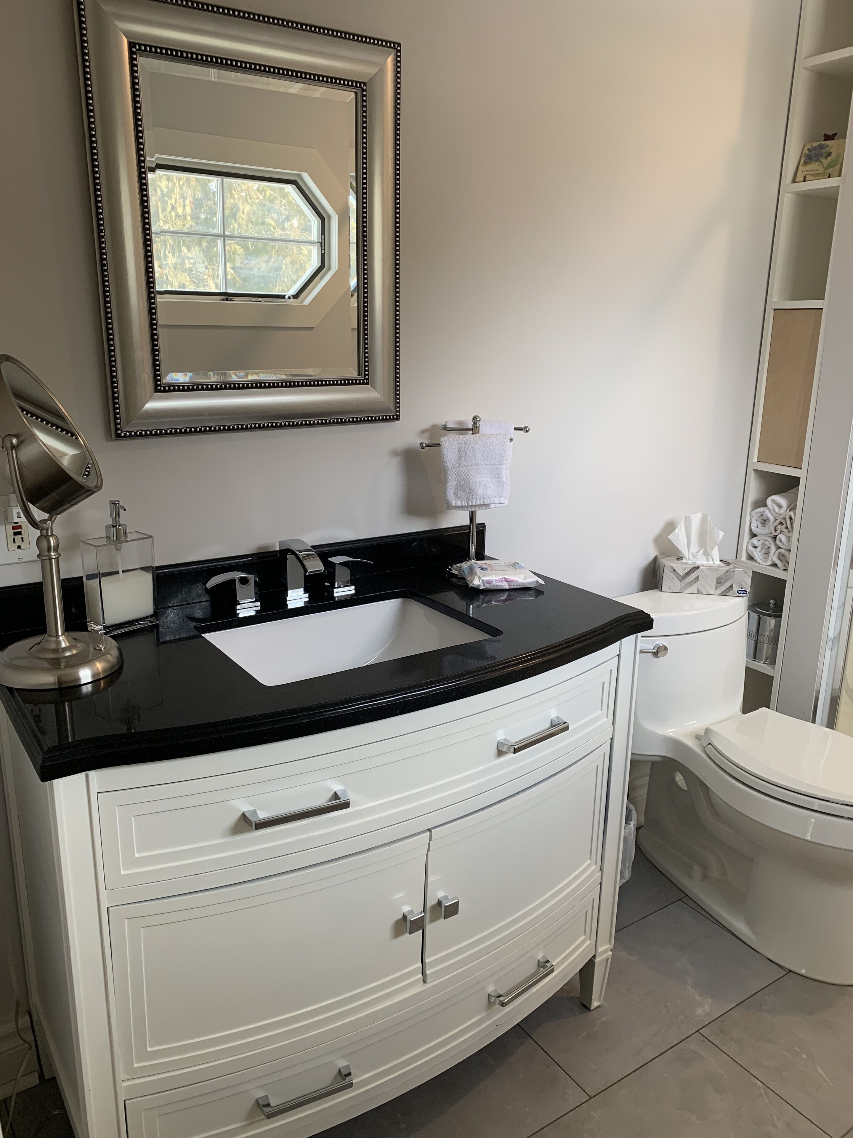 A bathroom with a white vanity, black countertop, and a mirror above the sink.