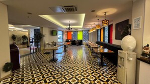 A hotel lobby with a patterned floor, seating areas, and a reception desk.