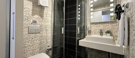 A bathroom with a glass-enclosed shower, a toilet, a sink, and a mirror.