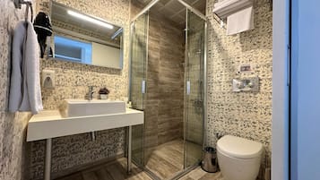 A modern bathroom with a glass-enclosed shower, a white sink, and a toilet.