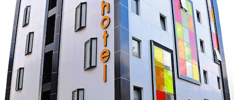 A modern hotel building with a prominent 'Tempo Hotel' sign, large windows, and a distinctive facade with colorful panels.