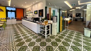 Ein modernes Café mit einer zentralen Theke, Regalen und einem gemusterten Boden.