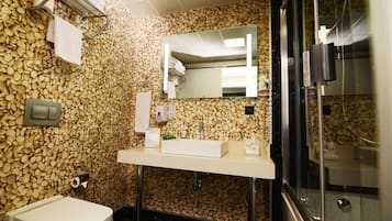 A bathroom with a pebble-patterned wall, a white sink, a mirror, and a toilet.