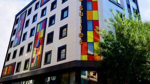 Un moderno edificio de hotel con fachada colorida, varias ventanas y cielo despejado.