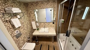 Un baño con pared de piedras, un lavabo, un inodoro y una ducha.