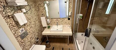A bathroom with a pebble wall, a sink, a toilet, and a shower.