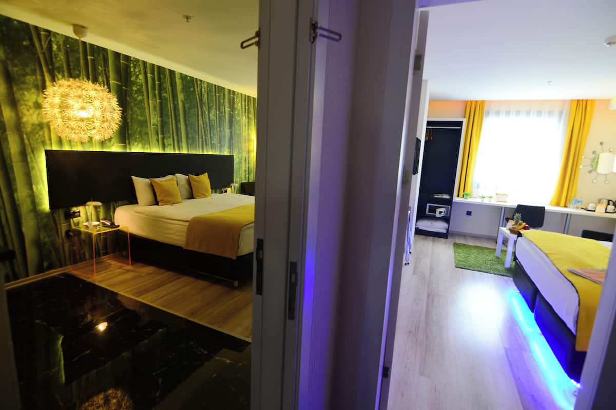 Une chambre d’hôtel avec un lit, une table de chevet et une grande fenêtre avec des rideaux.