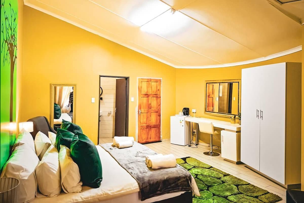 Una habitación de hotel con una cama, un escritorio, un espejo, un armario y una puerta.