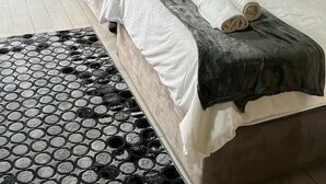 A room with two beds, a green wall mural, a window with curtains, and a patterned rug. - Musina Hotel (Musina)
