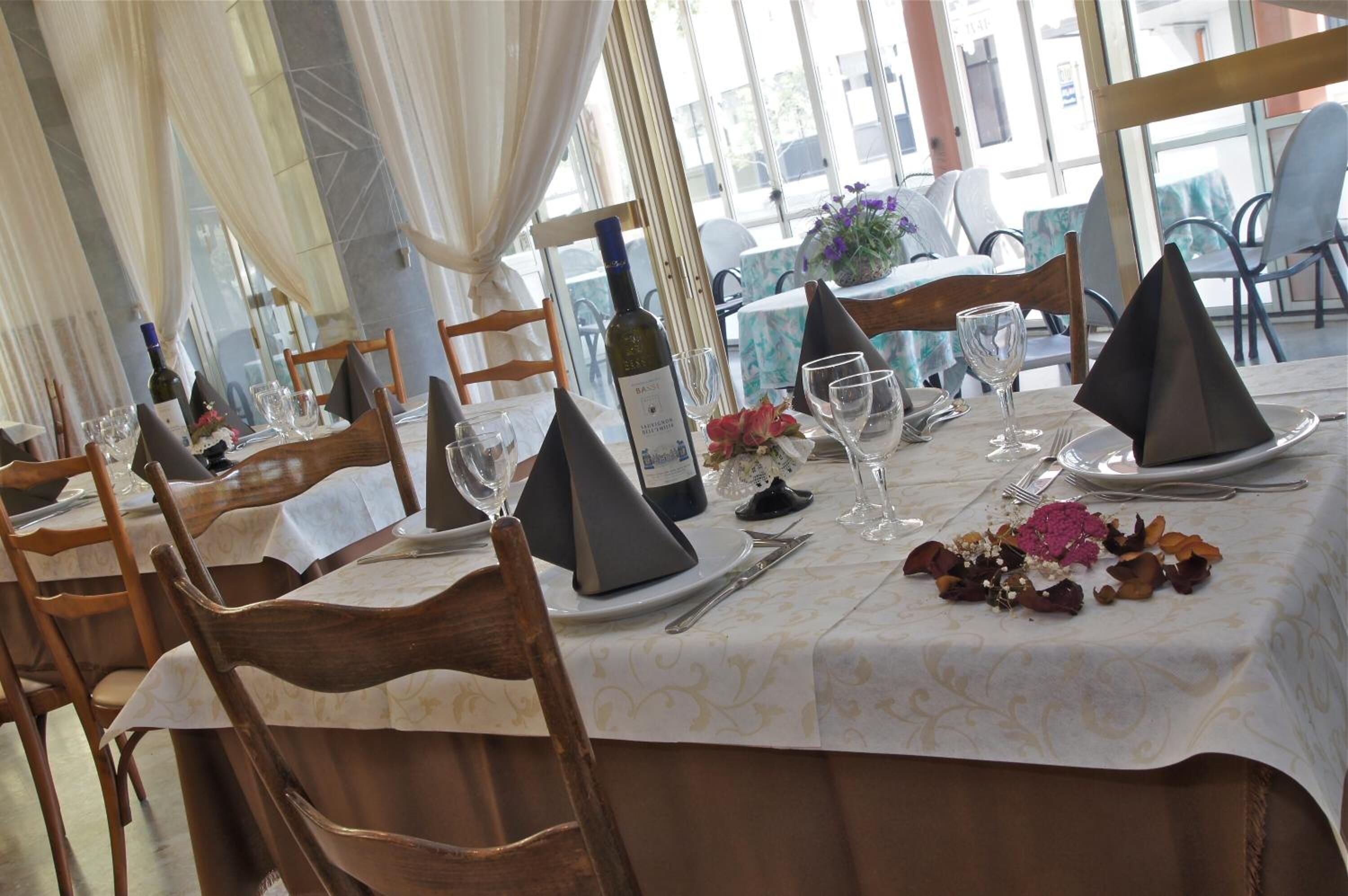 A dining table set with chairs, a bottle of wine, and a vase with flowers.