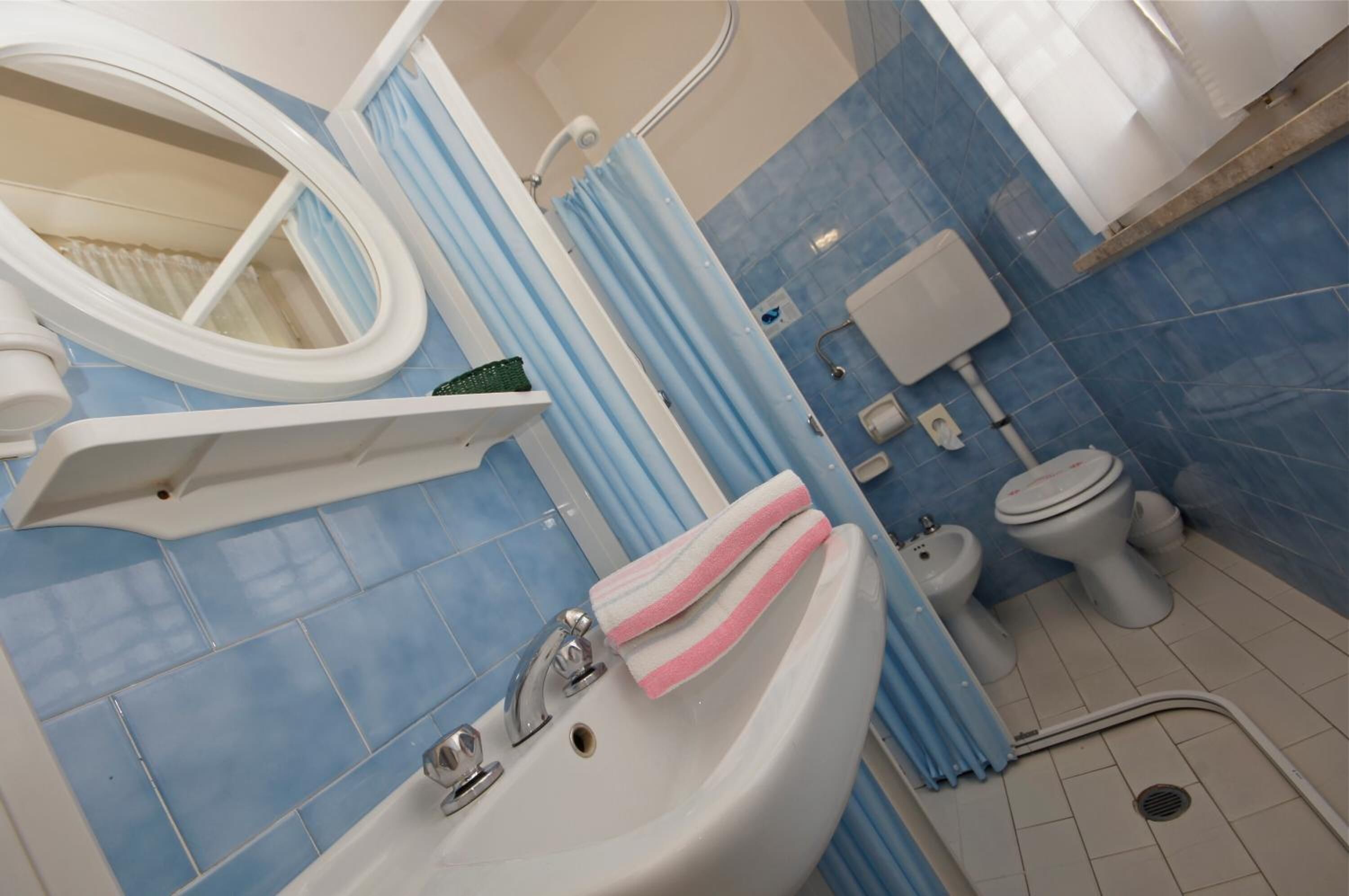 A bathroom with a sink, toilet, bidet, and shower area.