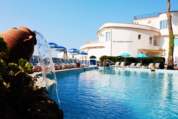Una piscina al aire libre, sillones reclinables de piscina