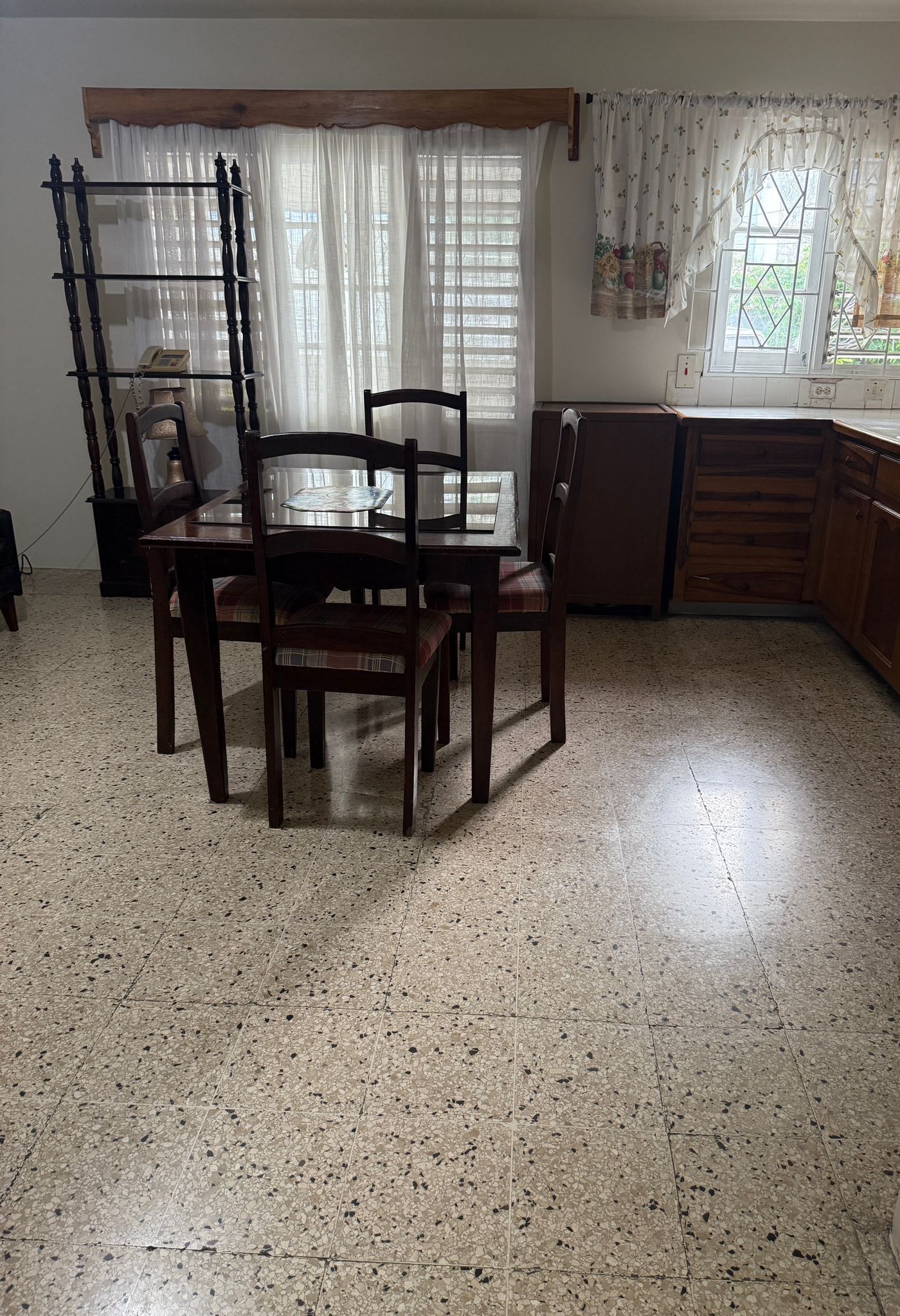 Un comedor con una mesa y sillas de madera, un armario de madera y una ventana con cortinas.