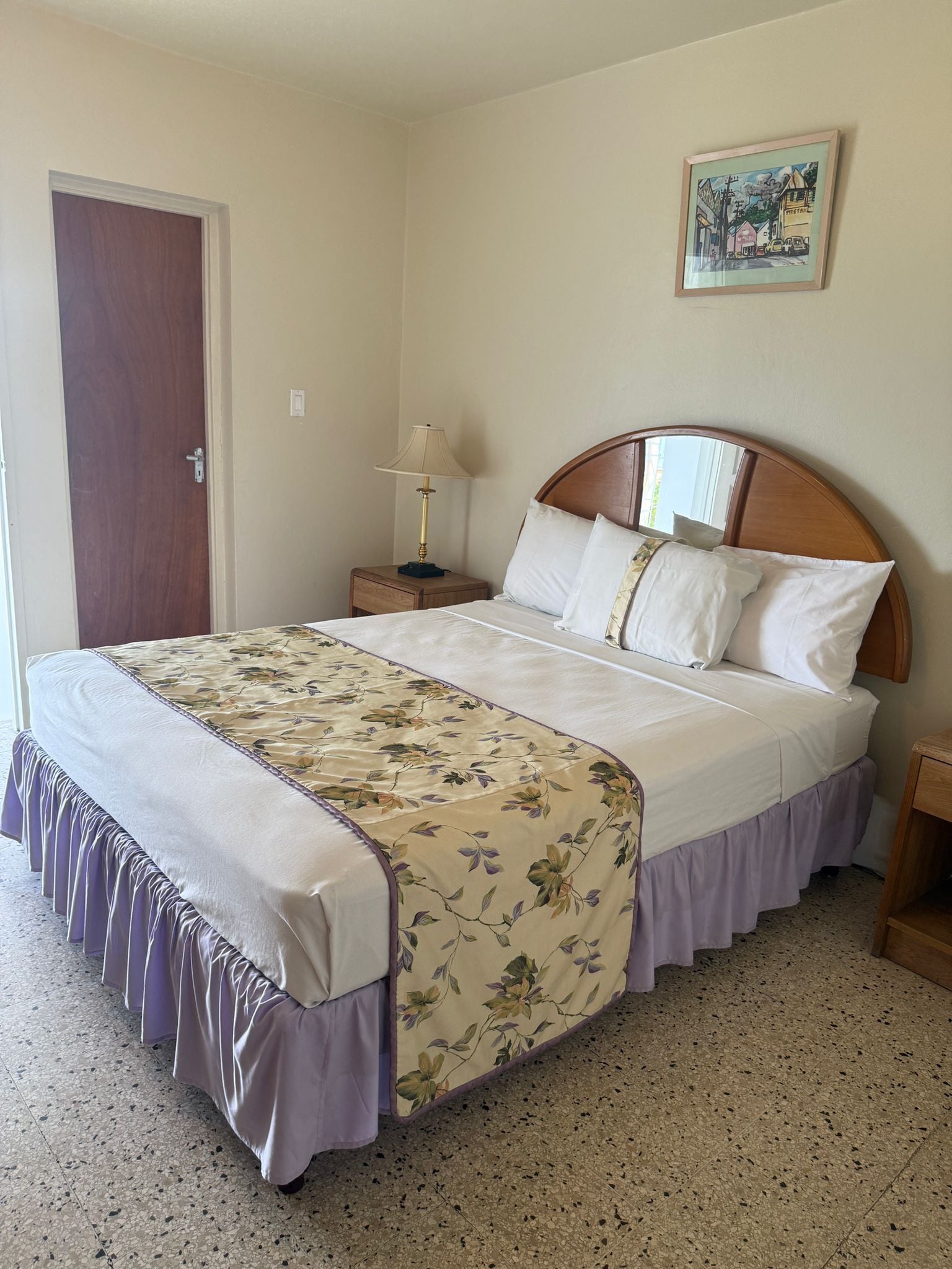 Una cama bien hecha con una colcha estampada de flores y un cabecero de madera.