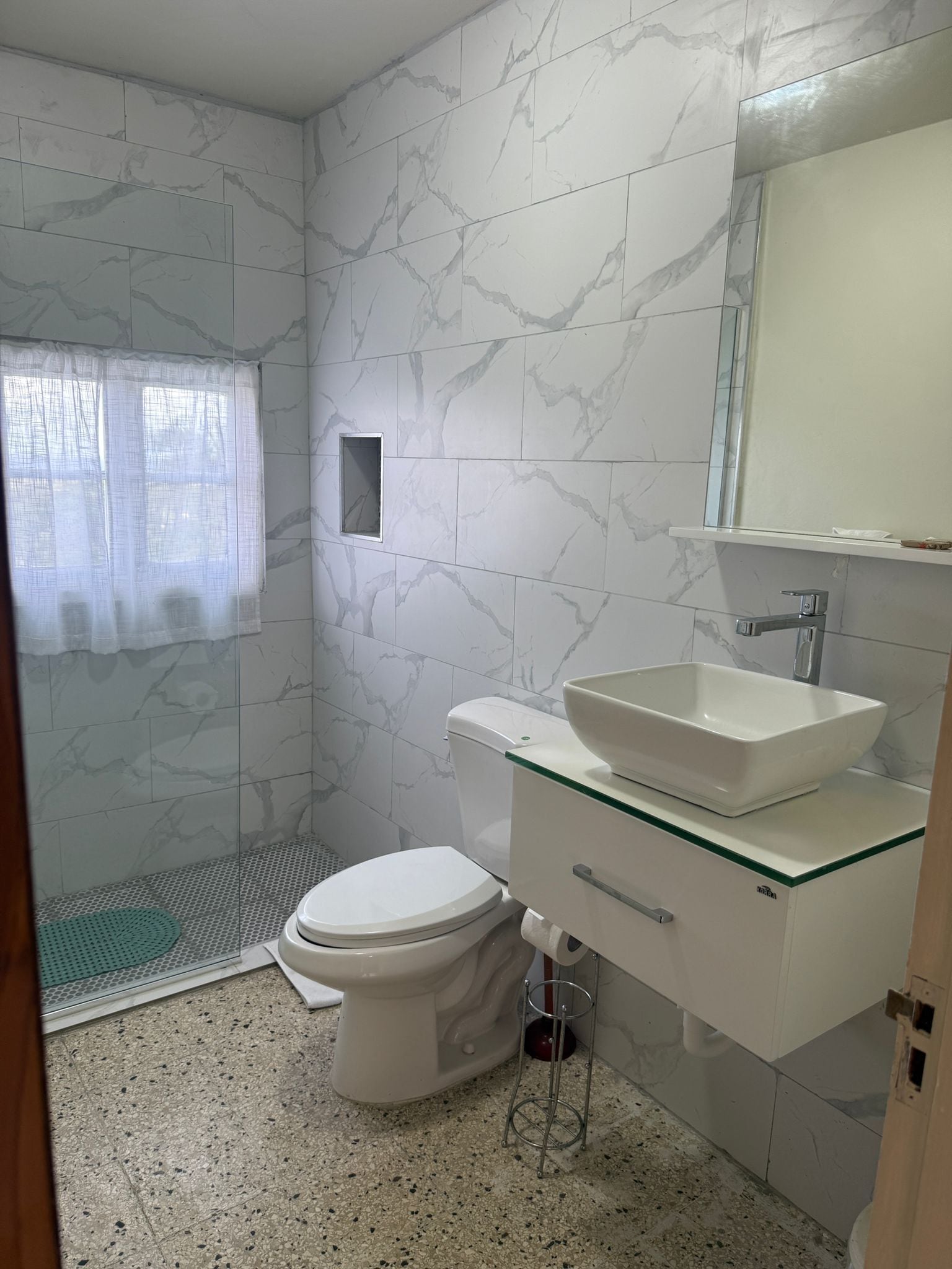 A bathroom with a toilet, sink, and shower area.