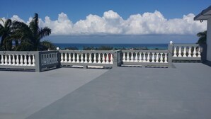 A balcony with white balustrades overlooking a coastal view. - Palm View Guesthouse and Conference Centre (Montego Bay)