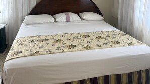 A bed with a floral bedspread, a wooden headboard, and white bedding. - Palm View Guesthouse and Conference Centre (Montego Bay)