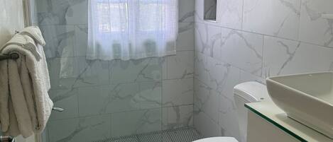 A bathroom with a shower, toilet, and sink.