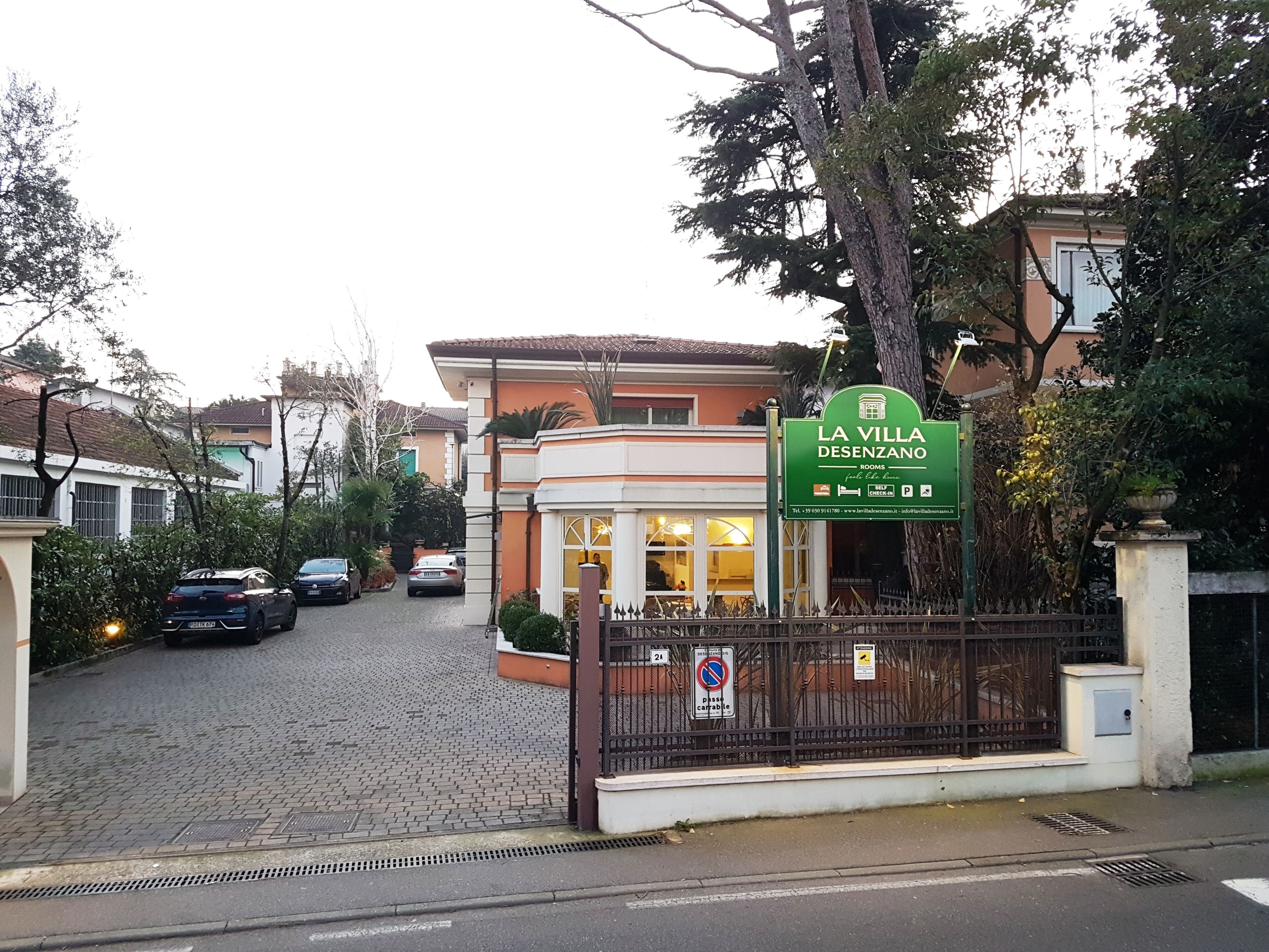 A hotel entrance with a sign reading "LA VILLA DESENZANO" and a gated driveway.