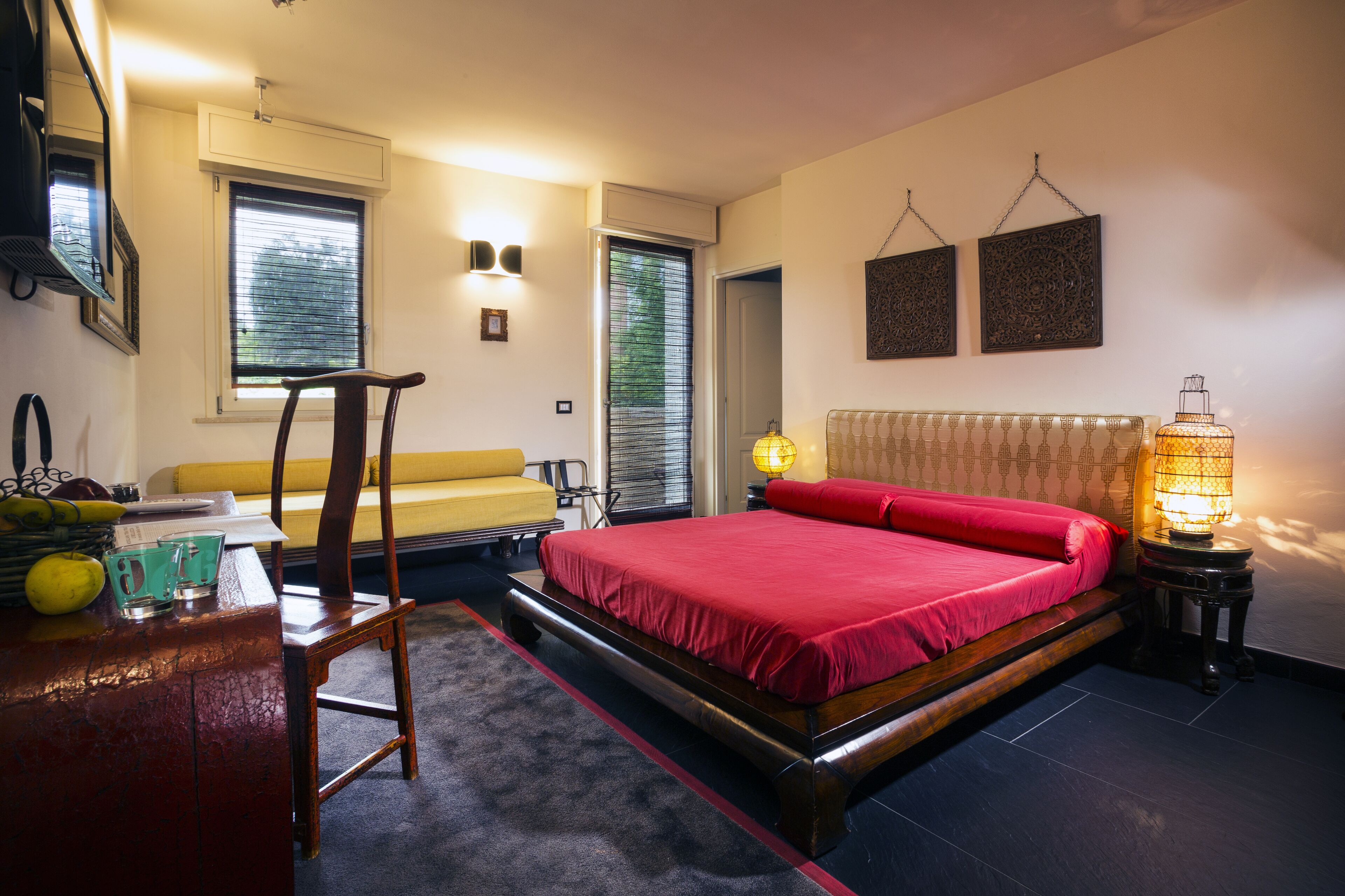 Un dormitorio con cama, escritorio, silla, lámpara y ventana.