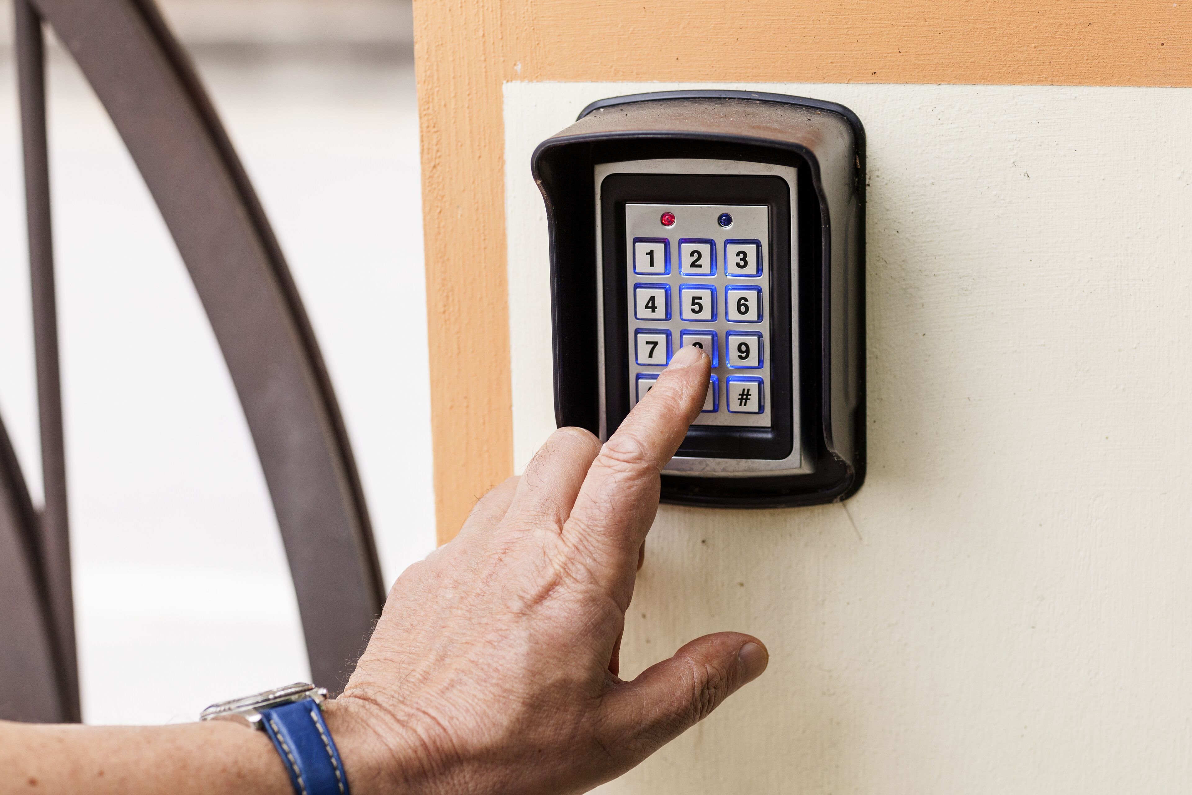 Een hand drukt op een keypad bij een deur.
